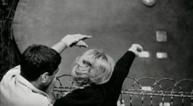 Black and white photo of the back of people’s heads as they throw small pieces of paper into the air.