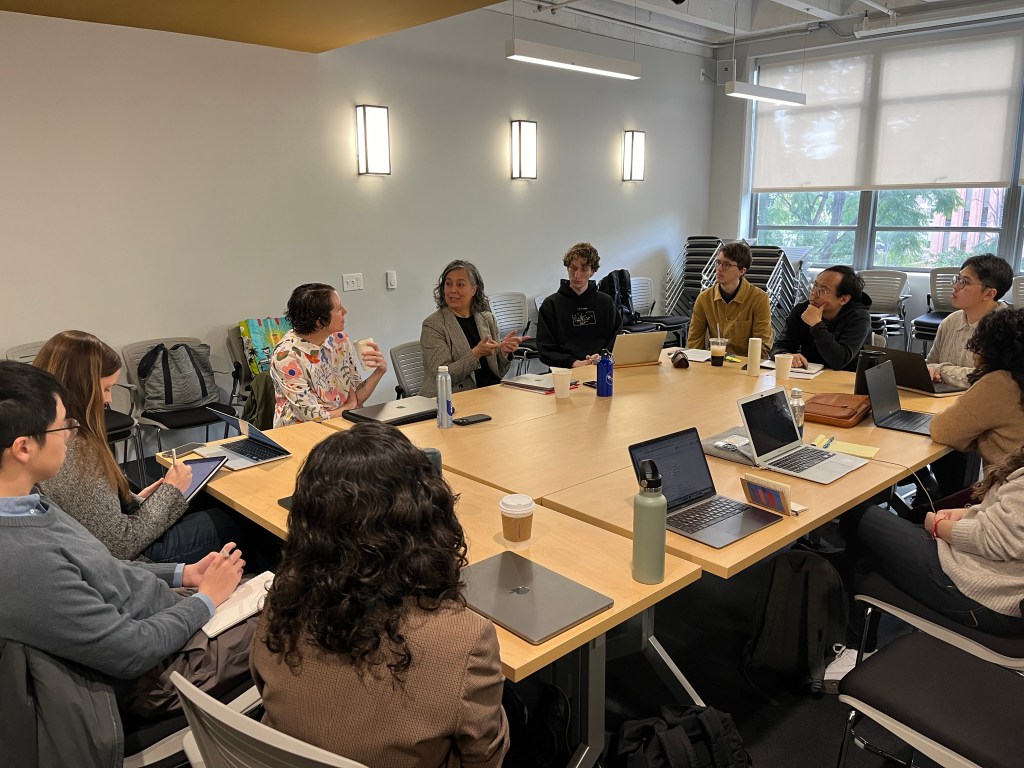 A handful of people sit around a conference table, deep in discussion.