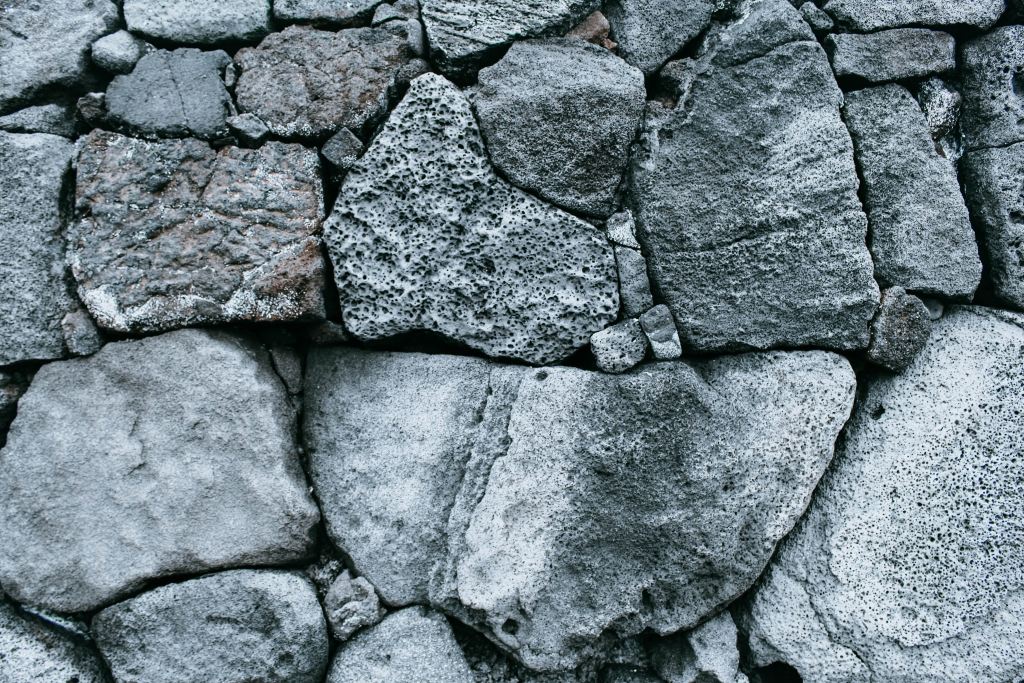 An image of rocks arranged in what seems like a wall. They are various shades of grey, and lots of pores are visible.