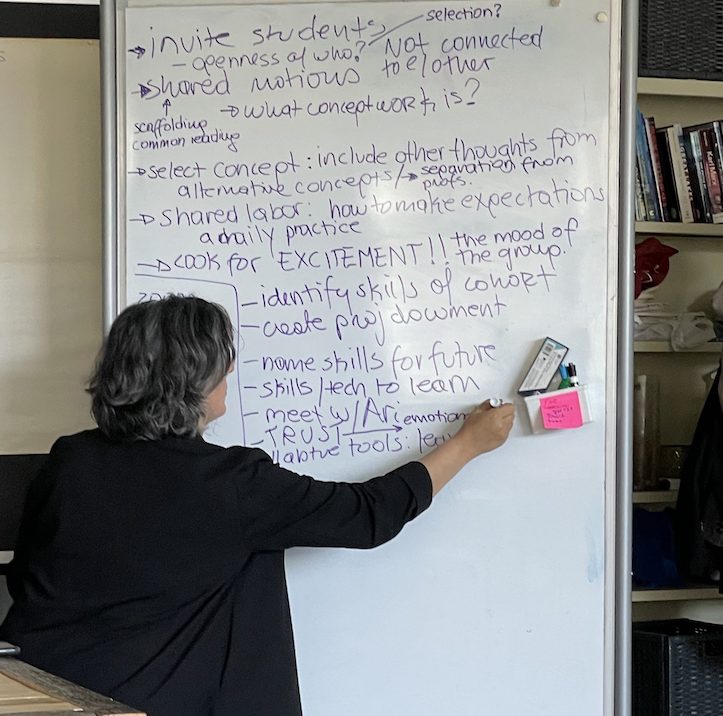 A person writes on a tall whiteboard.