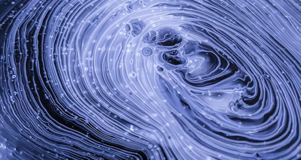 An abstract rendering of what looks like wavy lines of paint, extending in nesting circles; it evokes electricity and energy.