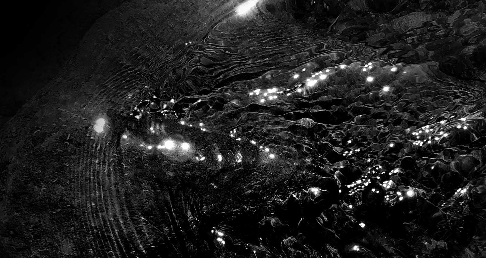 A black-and-white photo of ripples on the surface of water.