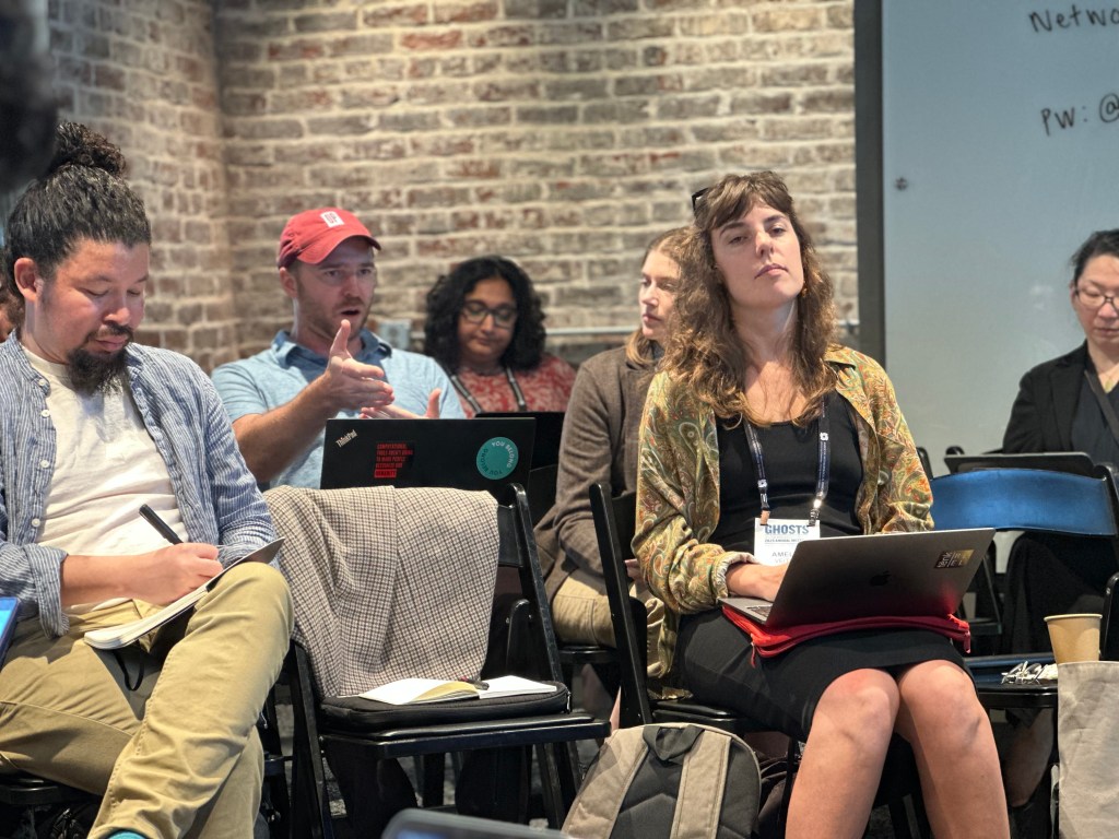 Michael Ralph speaks while sitting amongst other workshop attendees.