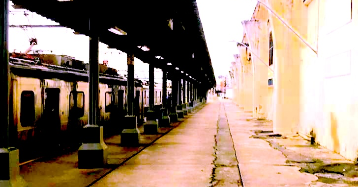 A train platform with a passing train.