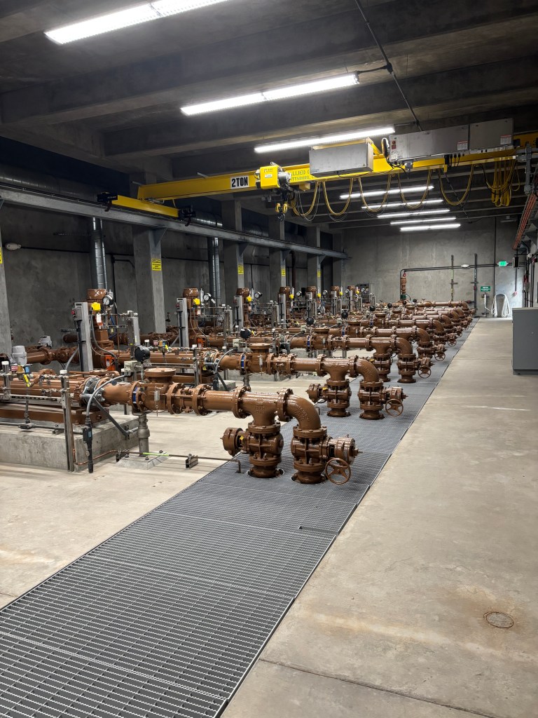 A row of hefty brown pipes in a concrete room.
